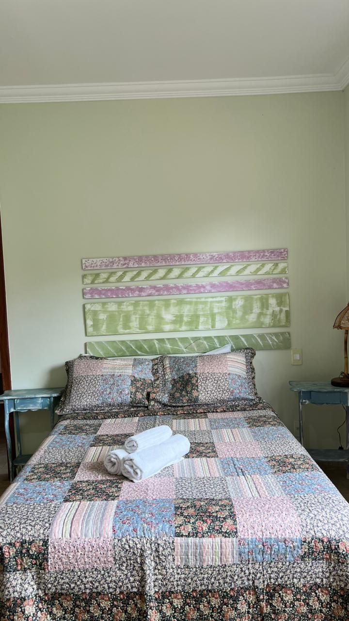 A bed with a floral-patterned quilt, two rolled towels, and a headboard with striped panels.