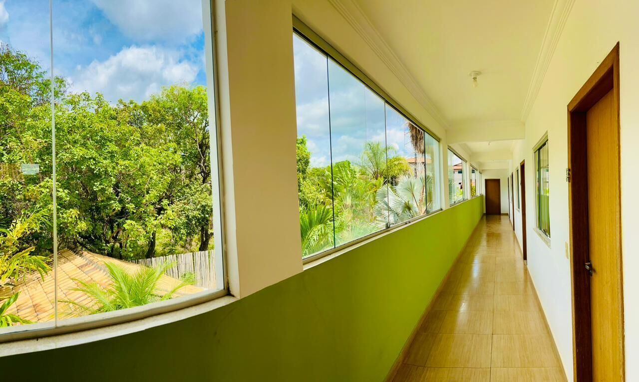 A corridor with large windows, a green wall, and a wooden floor.