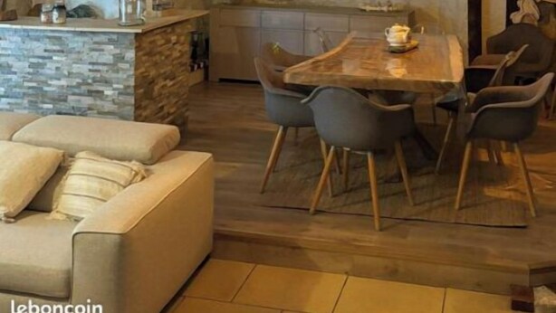 A cozy dining area with a stone wall backdrop, a wooden dining table, and modern chairs. - Semi-troglodyte gite near Amboise (Nazelles-Négron)