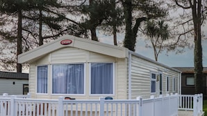 Ein Caravan mit weißer Außenfarbe, einer überdachten Veranda und einem umzäunten Deckbereich.