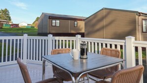 Eine Terrasse mit Tisch und Korbstühlen, mit Blick auf eine Reihe von Holoheimzügen.