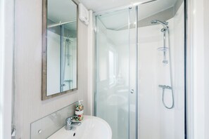 Une salle de bain moderne avec une douche à parois de verre, un lavabo blanc et un miroir.