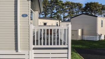 A mobile home with a white exterior, a porch with a railing, and a small window.