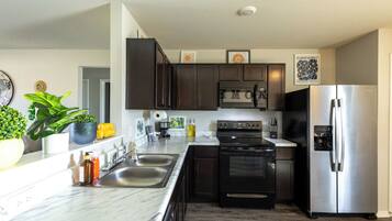 Una cucina moderna con mobili scuri, elettrodomestici in acciaio inossidabile, un piano di lavoro in marmo e una pianta in vaso.