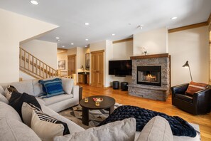 A living room with a fireplace, a sofa, a coffee table, and a television. - Big Sky Getaway | Fireplace + Shared Pool + Grill (Big Sky)