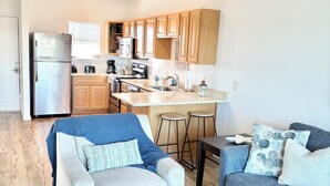 Un apartamento moderno con cocina, dos sofás, una mesa de centro y un ventilador de techo.