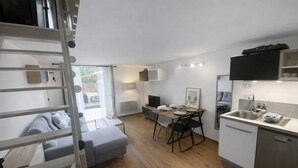 Un espace de vie compact comprenant un lit en mezzanine, un coin repas et une kitchenette.