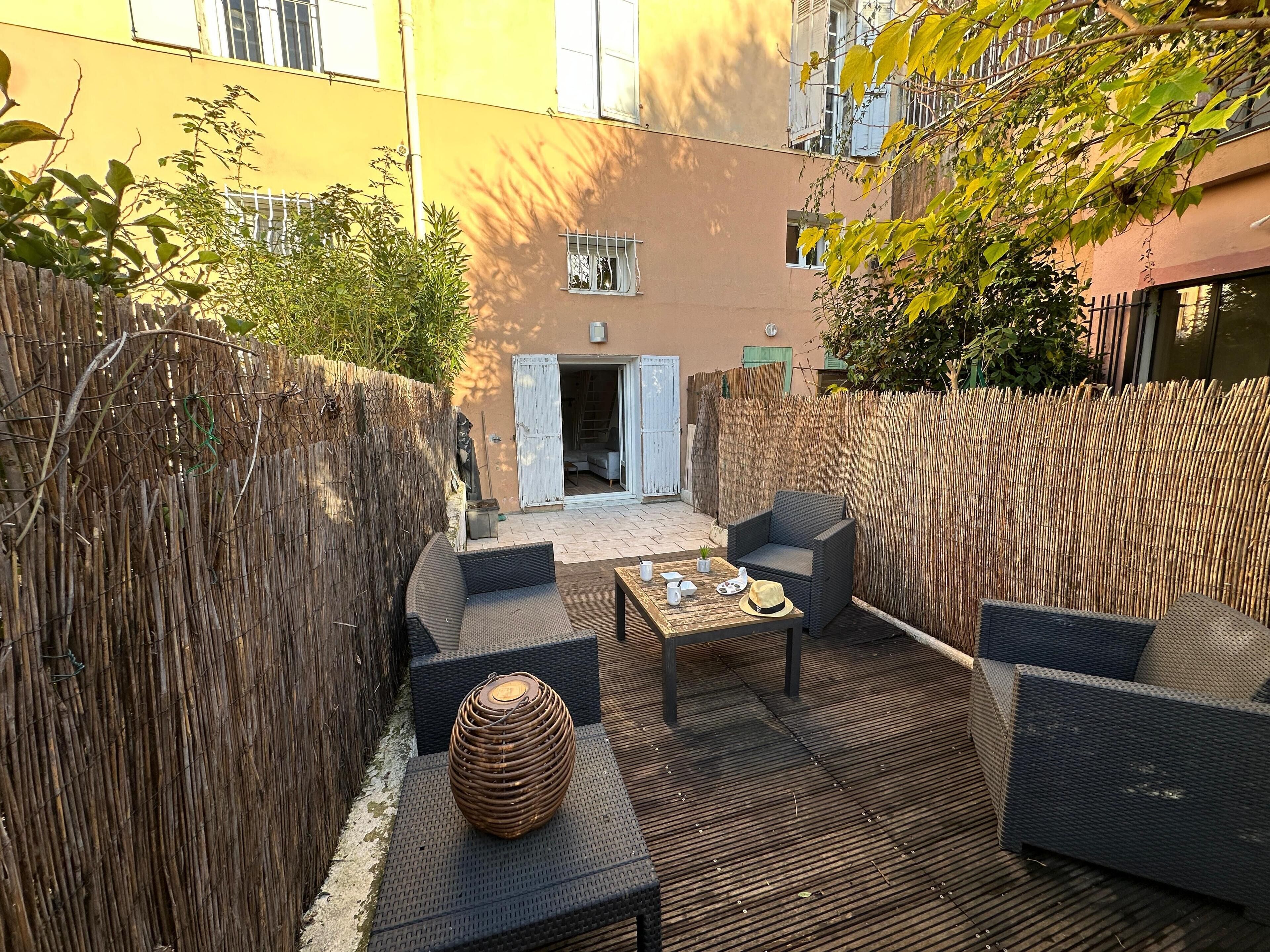 An outdoor patio area with wicker furniture, a woven table, and a decorative vase.