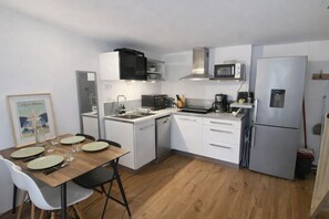 Una cucina compatta con mobili bianchi, un forno a microonde, una macchina da caffè e un frigorifero.