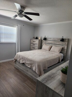 A bedroom with a bed, a ceiling fan, a window with curtains, and a bedside table with a plant. - The Relax spot
golf, hospital, restaurants, raceway and shops near by. (Sebring)
