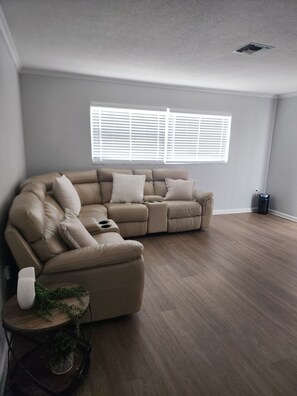 A sectional sofa in a room with hardwood flooring and a window with blinds. - The Relax spot
golf, hospital, restaurants, raceway and shops near by. (Sebring)