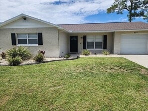 A single-story house with a garage, a front lawn, and a small garden area with various plants. - The Relax spot
golf, hospital, restaurants, raceway and shops near by. (Sebring)