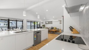 Una cucina moderna con lavastoviglie, una zona pranzo con tavolo e sedie e un soggiorno con divano e tavolino.
