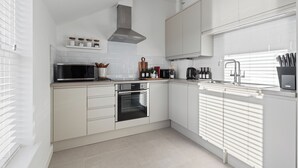 Eine moderne Küche mit weißen Schränken, einem eingebauten Backofen, einer Mikrowelle und einer Edelstahl-Dunstabzugshaube.