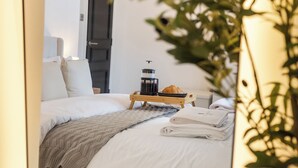 Ein ordentlich bezogenes Bett mit Kaffeemaschine, einem Croissant und gefalteten Handtüchern.