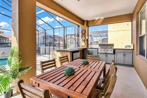 A spacious patio with a wooden table and chairs, a small pool, and a kitchen area with a grill. - Spacious 7BR Retreat w/ Pool & Game Room (Davenport)