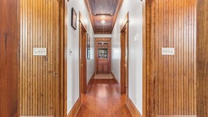 Un couloir en bois avec une porte centrale et des luminaires au plafond.