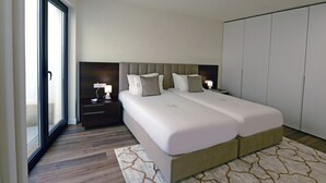 Een tweepersoonsbed met hoofdeinde, nachtkastjes met lampen, een grote garderobe en een kamerbreed tapijt met patroon.
