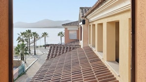 Ein Gebäude mit einer mit Fliesen versehenen Treppe, die zu einem Balkon mit Blick auf ein Gewässer und Berge führt.
