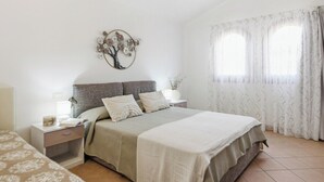 Ein Schlafzimmer mit einem Bett, Nachttischen, einer Wanddekoration und einem Fenster mit Vorhängen.
