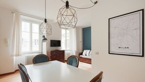 En matplats med ett vitt bord och stolar, en tv och en blå vägg.