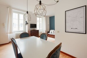 Ein Essbereich mit einem weißen Tisch und Stühlen, einem Fernseher und einer blauen Wand.