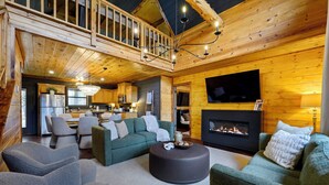 A spacious living area with a fireplace, a television, and a balcony. - Waterfront Cabin • Pond • Hot Tub • Great Location (Broken Bow)
