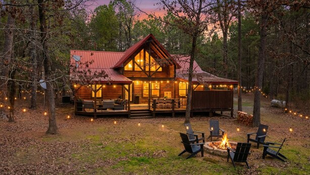 A log cabin with a deck, outdoor seating, and a fire pit. - Waterfront Cabin • Pond • Hot Tub • Great Location (Broken Bow)