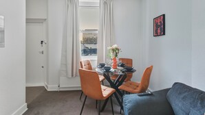 Ein Essbereich mit einem runden Tisch, orangefarbenen Stühlen und einem blauen Sofa.