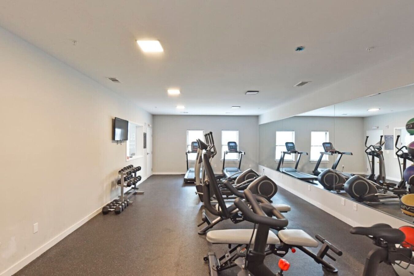 Un gimnasio con cintas de correr, elípticas y pesas libres.