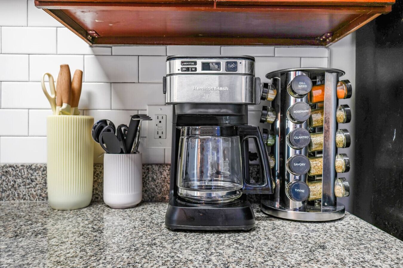 A kitchen with a coffee maker, a spice rack, and a utensil holder.