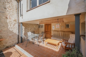 Un patio con una mesa, sillas, un sofá y un banco de madera.
