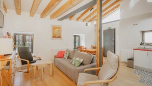 Un salon moderne comprenant un canapé, des fauteuils, une table à manger et un coin cuisine.