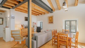 Un intérieur moderne avec un plafond en bois, un canapé gris, une table à manger en bois et des chaises.