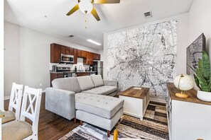 Un salon moderne avec un canapé d’angle, une table basse et une fresque murale représentant une carte géographique.