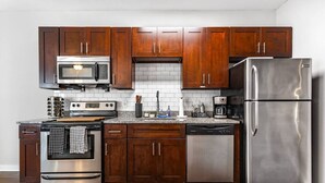 A modern kitchen with dark wooden cabinets, stainless steel appliances including a refrigerator, oven, and microwave, and a granite countertop. - `Amazing value, convenient location!` +Free prkng! (Nashville)