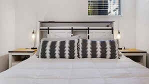 A bed with a white quilt, two bedside tables with lamps, a headboard with a window, and a patterned pillow. - `Amazing value, convenient location!` +Free prkng! (Nashville)