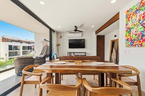 Un salon moderne avec une table à manger en bois, un canapé et un téléviseur.