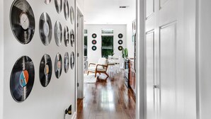 Un couloir orné de disques en vinyle accrochés au mur, un coin repas avec des chaises et une cuisine équipée de placards.