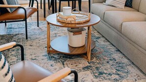 A living room with a sofa, chairs, a coffee table, and a dining area with a table and chairs. - The Marigold at Mill Creek (Topping)