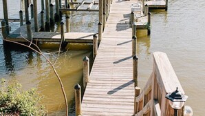 A wooden dock leading to a covered structure with two chairs on a small platform. - The Marigold at Mill Creek (Topping)