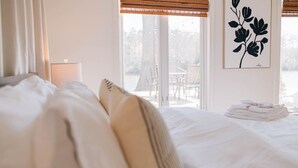A neatly made bed with pillows, a stack of towels, and a framed floral artwork on the wall. - The Marigold at Mill Creek (Topping)