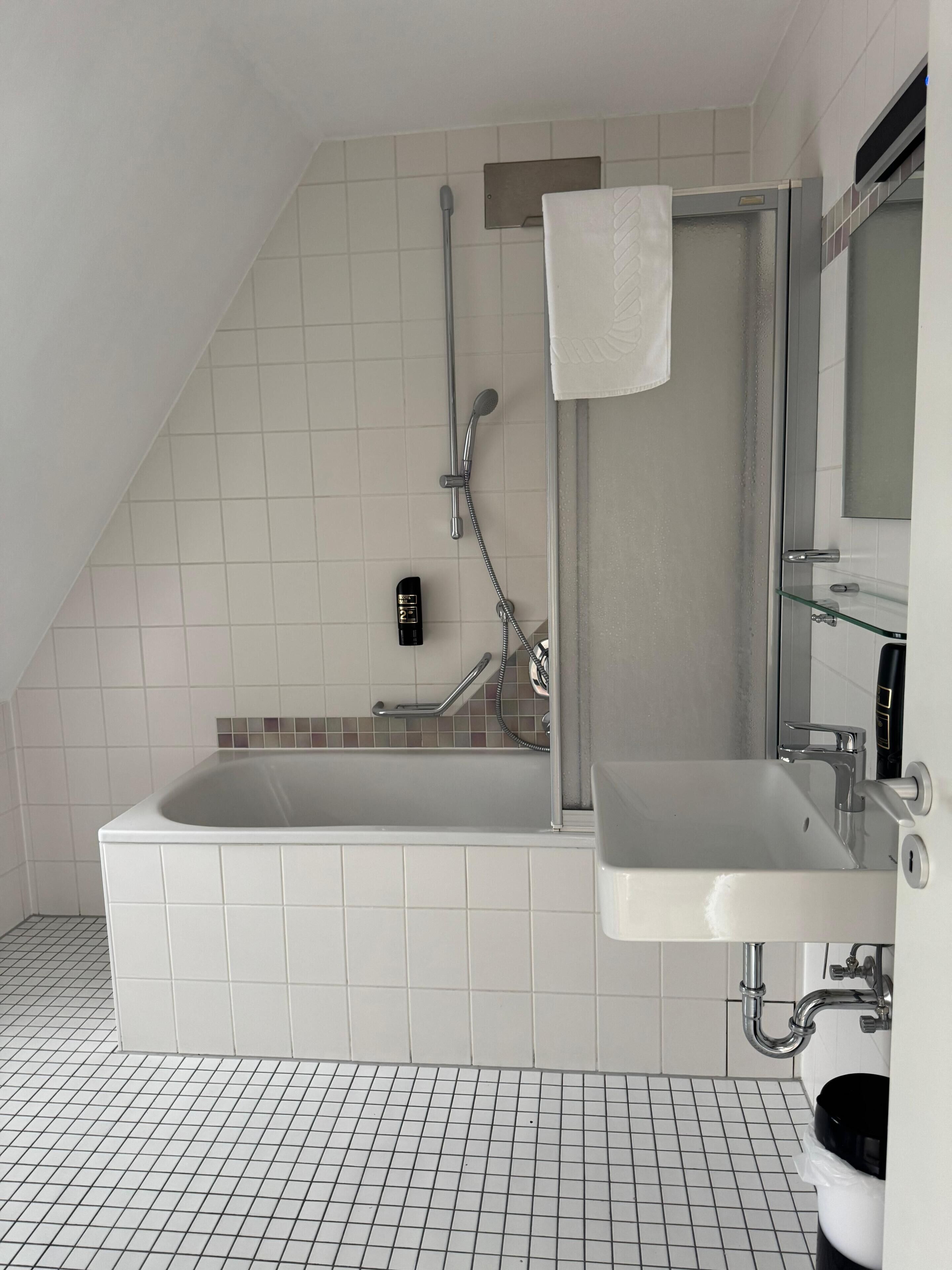 A modern bathroom with a bathtub, a shower, a sink, and a mirror.