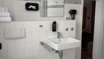 Ein modernes Badezimmer mit einem weißen Waschbecken, einem Spiegel, einem Handtrockner und einer Toilette.
