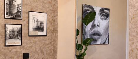 An art gallery with framed photographs and a large painting on the wall.