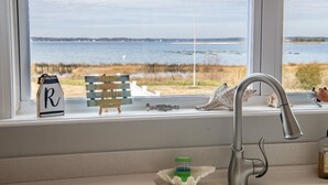 Una ventana de cocina con vista al agua y a la playa.