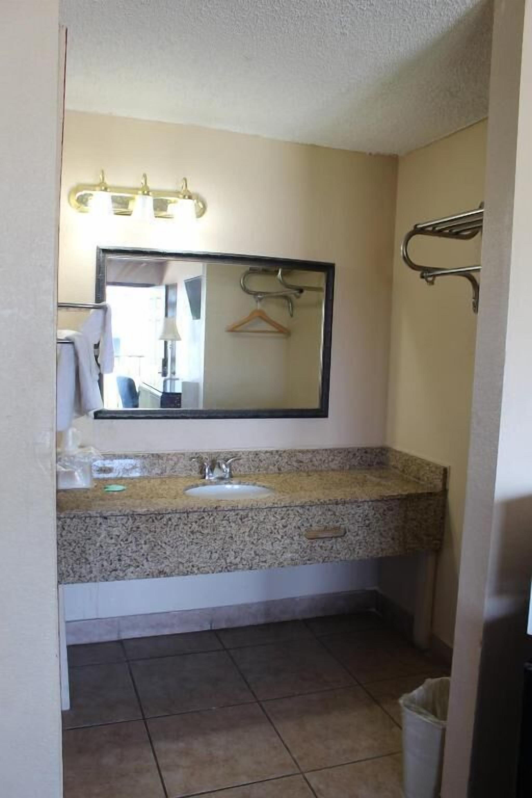 Un bagno con lavabo in granito, uno specchio e un porta asciugamani.