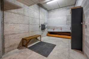 A room with a concrete wall, a wooden bench, a black mat, and a black door. - GuestHost - Charming studio in Tarvisio, ideal for 3 people, equipped with a balcony offering breathtaking views of the Alps. The accommodation is perfect for a romantic getaway or a nature adventure. Tarvisio is a paradise for winter sports enthusiasts  (Tarvisio)