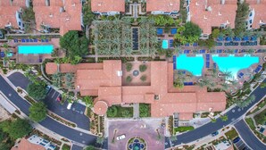 An aerial view of a resort with multiple buildings, a central pool, and a circular fountain. - Heritage Hideaway | 2BR Legacy Villa (La Quinta)