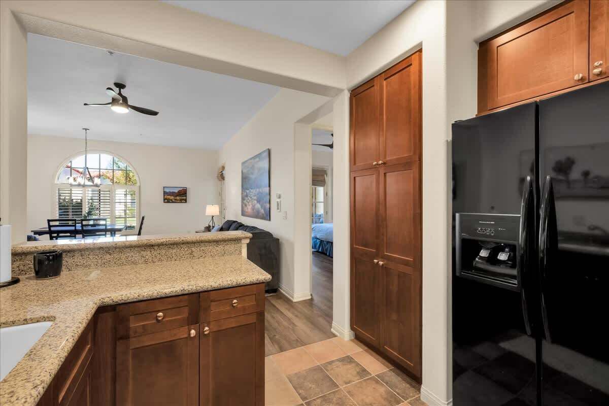 A kitchen with wooden cabinets, a black refrigerator, and a granite countertop.